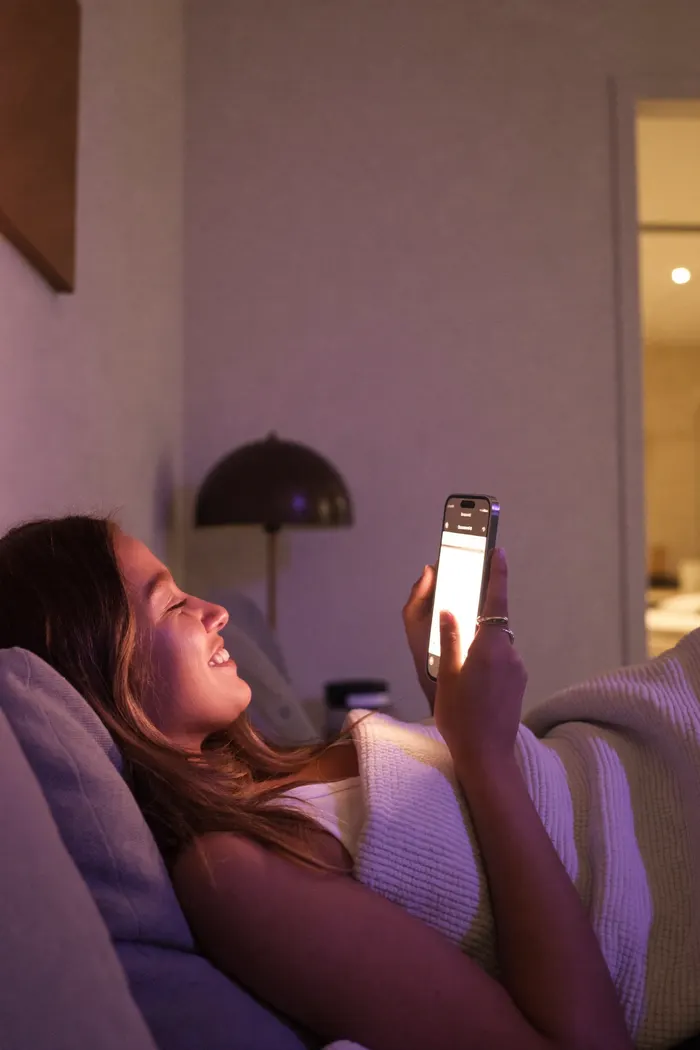Woman smiling at a chat with her AI companion on her phone at night