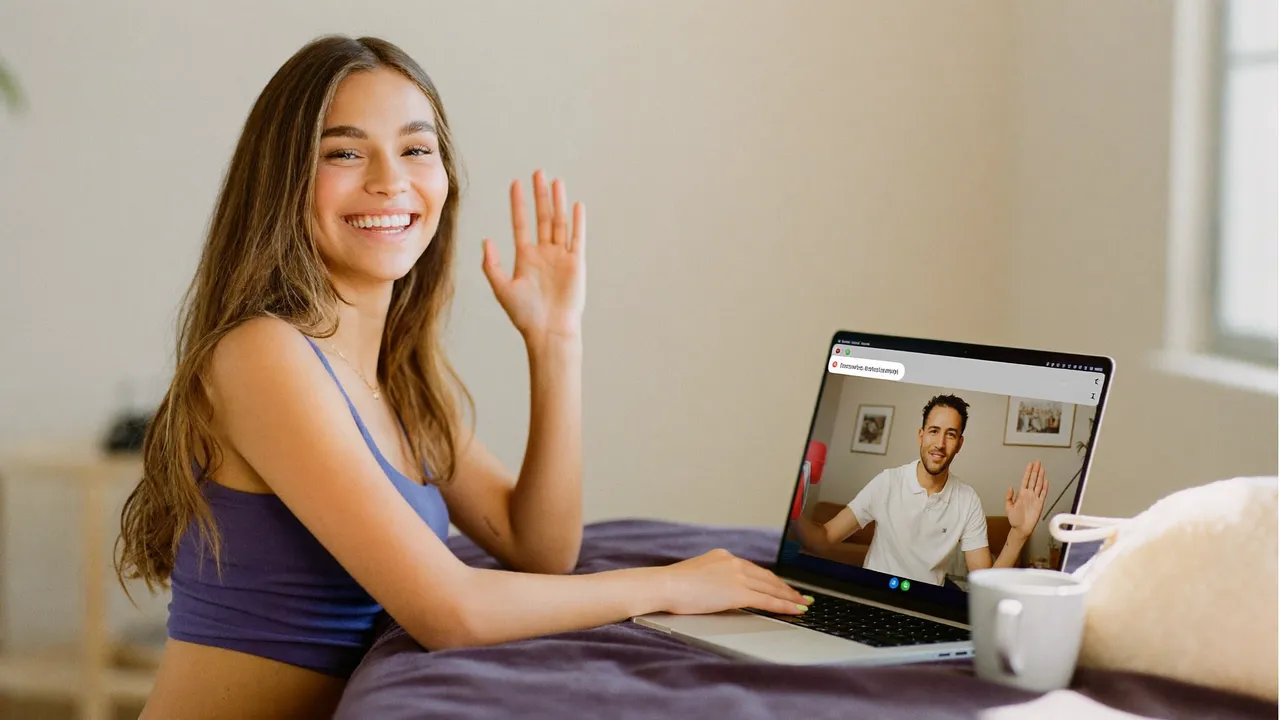 A smiling young woman waving to a new friend on a laptop video call